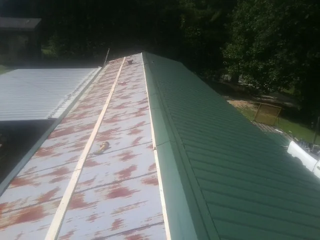 Old rusted panels beside newly installed green metal roofing — Wind Damage Roof Repair by Roofing Brothers in Zillah