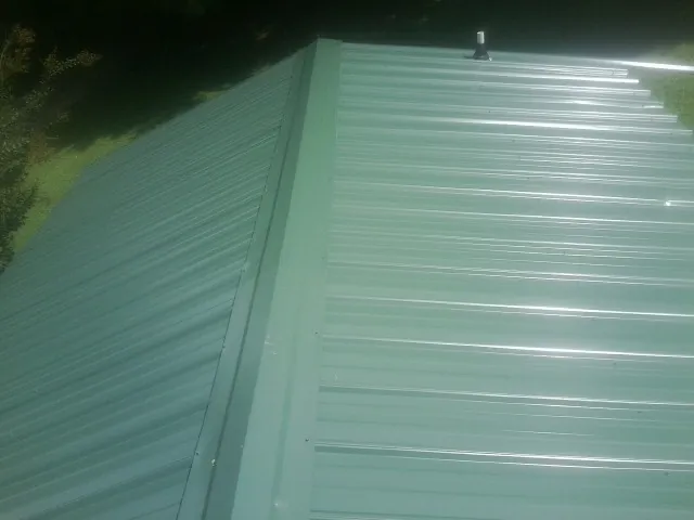 New green metal panels meeting at the ridge of a roof — Flat Roof Repair work by our crew in Zillah