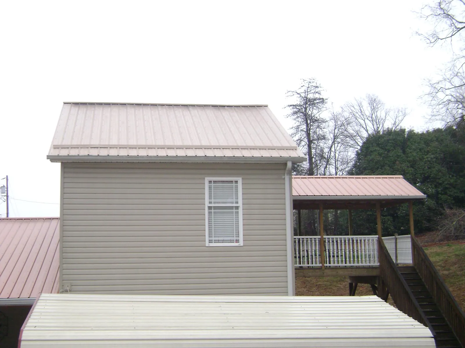 Tan metal roofs on a two story addition and attached porch, from a Roof Replacement job in Zillah